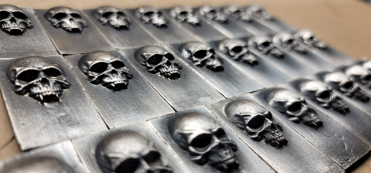 Angled group view of 2025 Kannibal Skull Bars in .999 fine silver, arranged in rows with raised skull relief