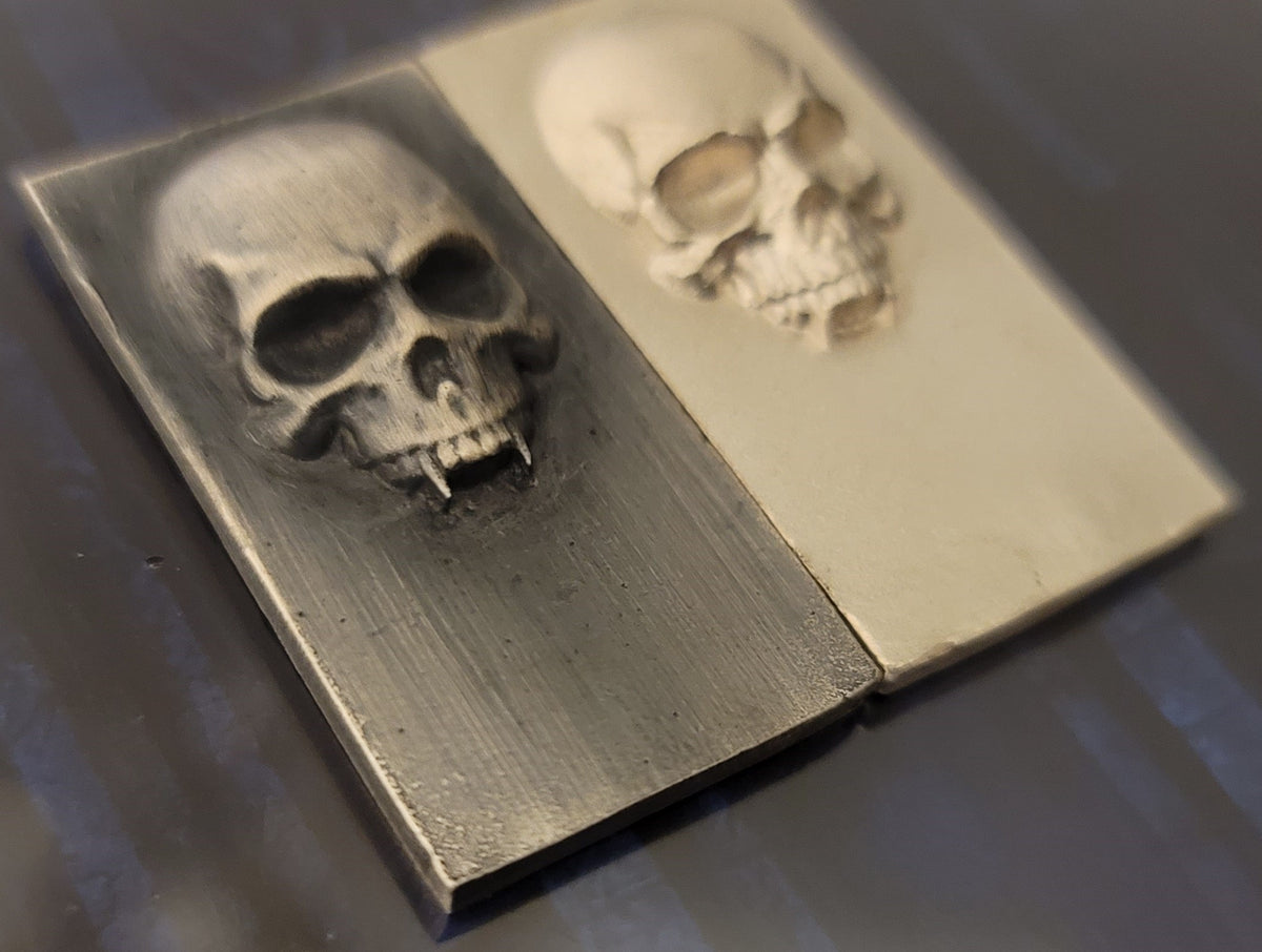 Close angled view of 2025 Kannibal Skull Bars in antique and matte finishes, showing raised skull relief in .999 fine silver