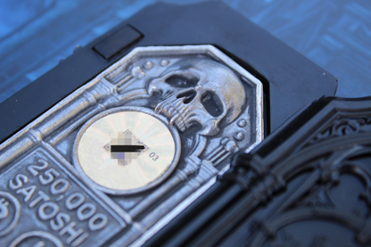 Angled close-up of The Reliquary .999 fine silver Bitcoin wallet showing the skull relief, hologram, and 250,000 Satoshi marking