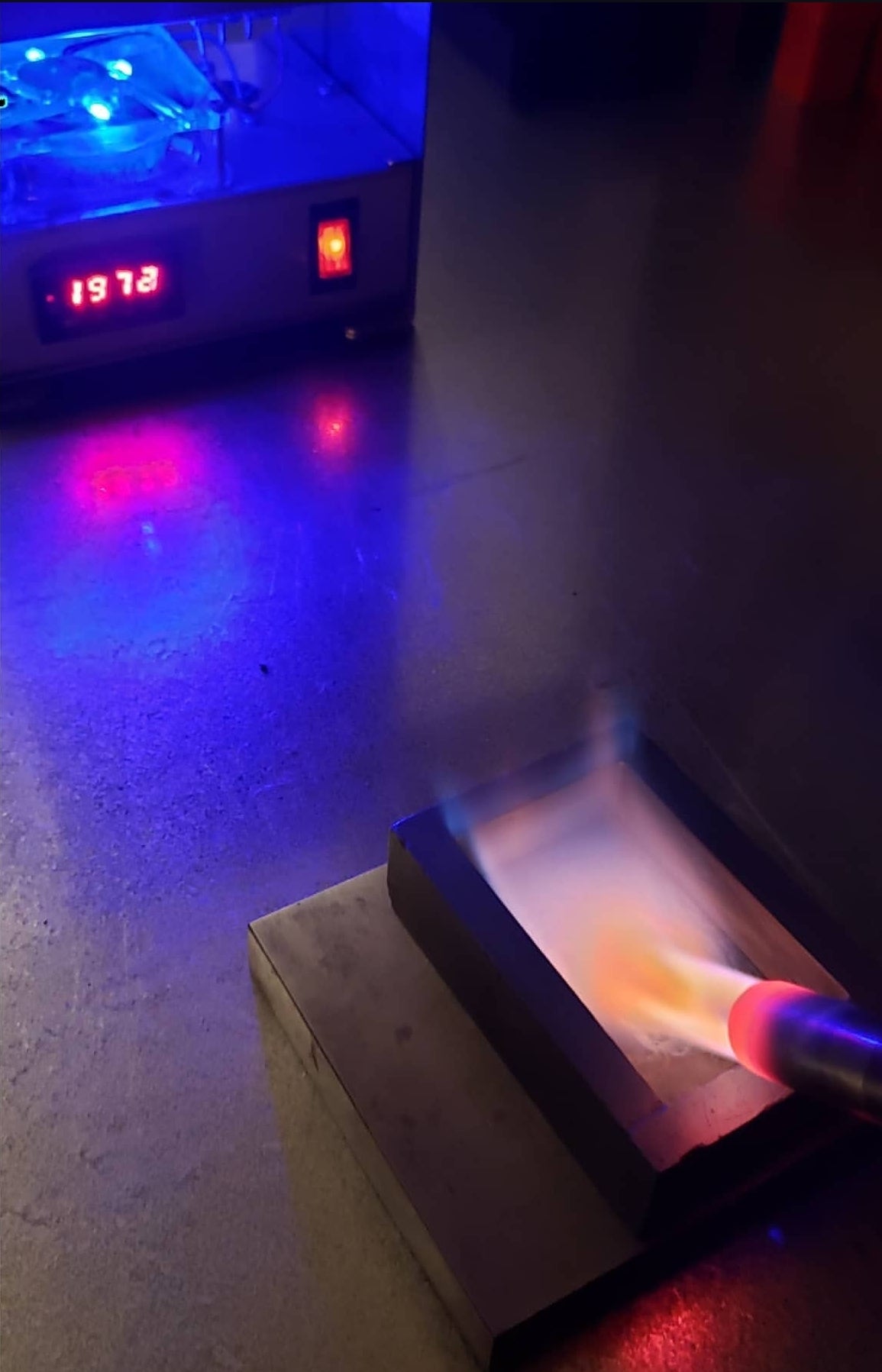 Torch heating a casting mold with a tabletop melting furnace in the background during the Kannibal Hektor silverworking process